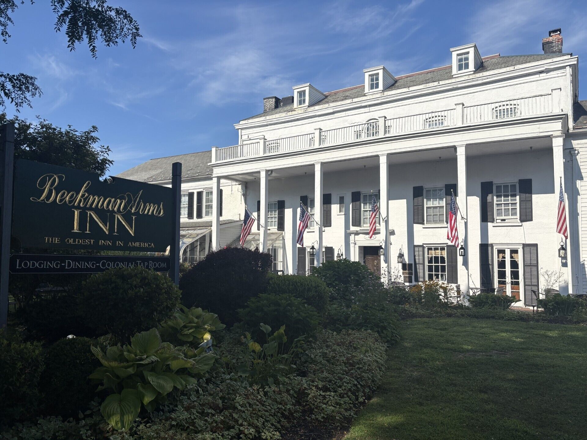 A historic Beekman Arms Inn with a colonial-style facade, multiple flags, and a well-maintained garden.