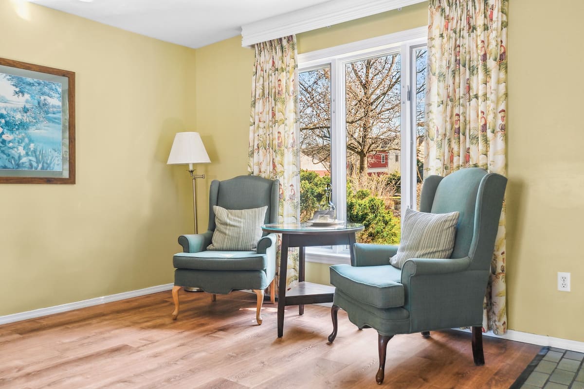 A room with two armchairs, a small table, and a lamp.