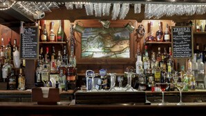 Un espace bar avec un assortiment de bouteilles d’alcool, un tableau affichant le menu et un décor rustique en bois.