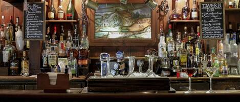 A bar area with a variety of liquor bottles, a menu board, and a rustic wooden backdrop.
