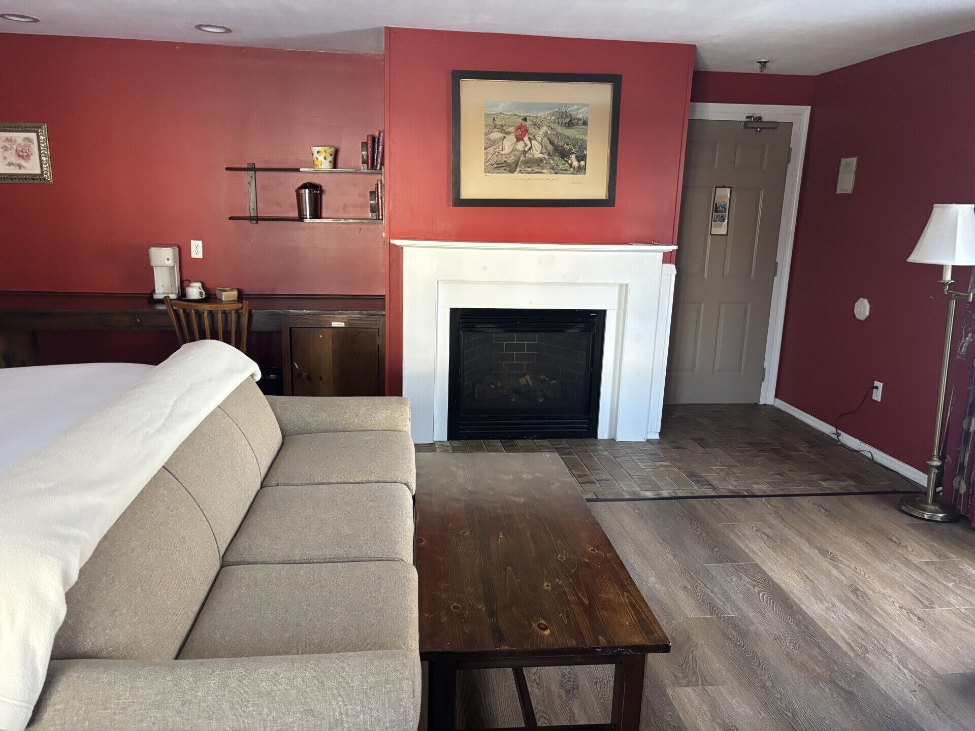 Une chambre d’hôtel avec un canapé, une table en bois, une cheminée, une bibliothèque et une porte.