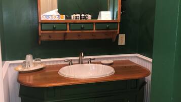 A bathroom with a wooden vanity, a white sink, and a mirror above it.