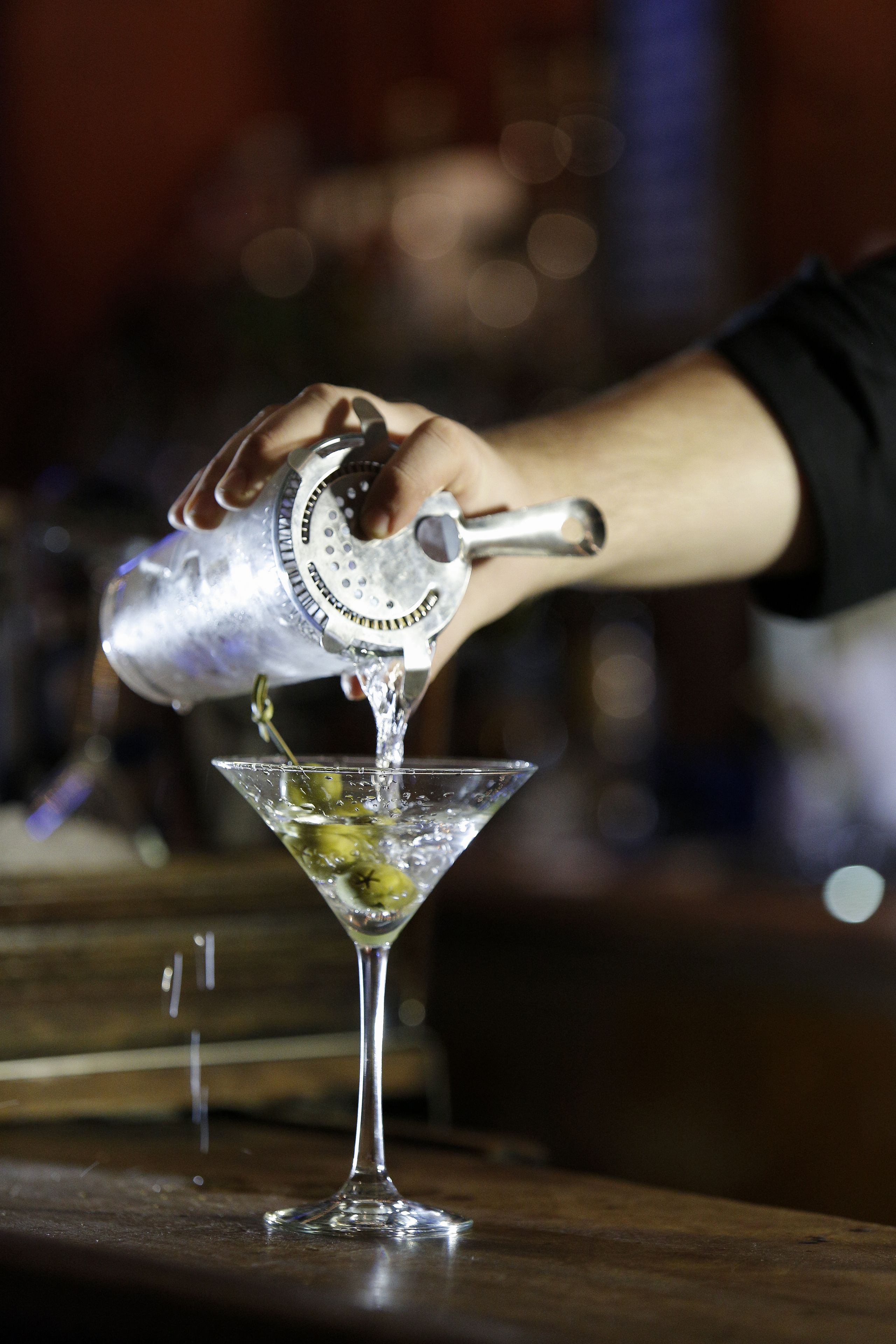 Eine Hand gießt ein Getränk in ein Martini-Glas.