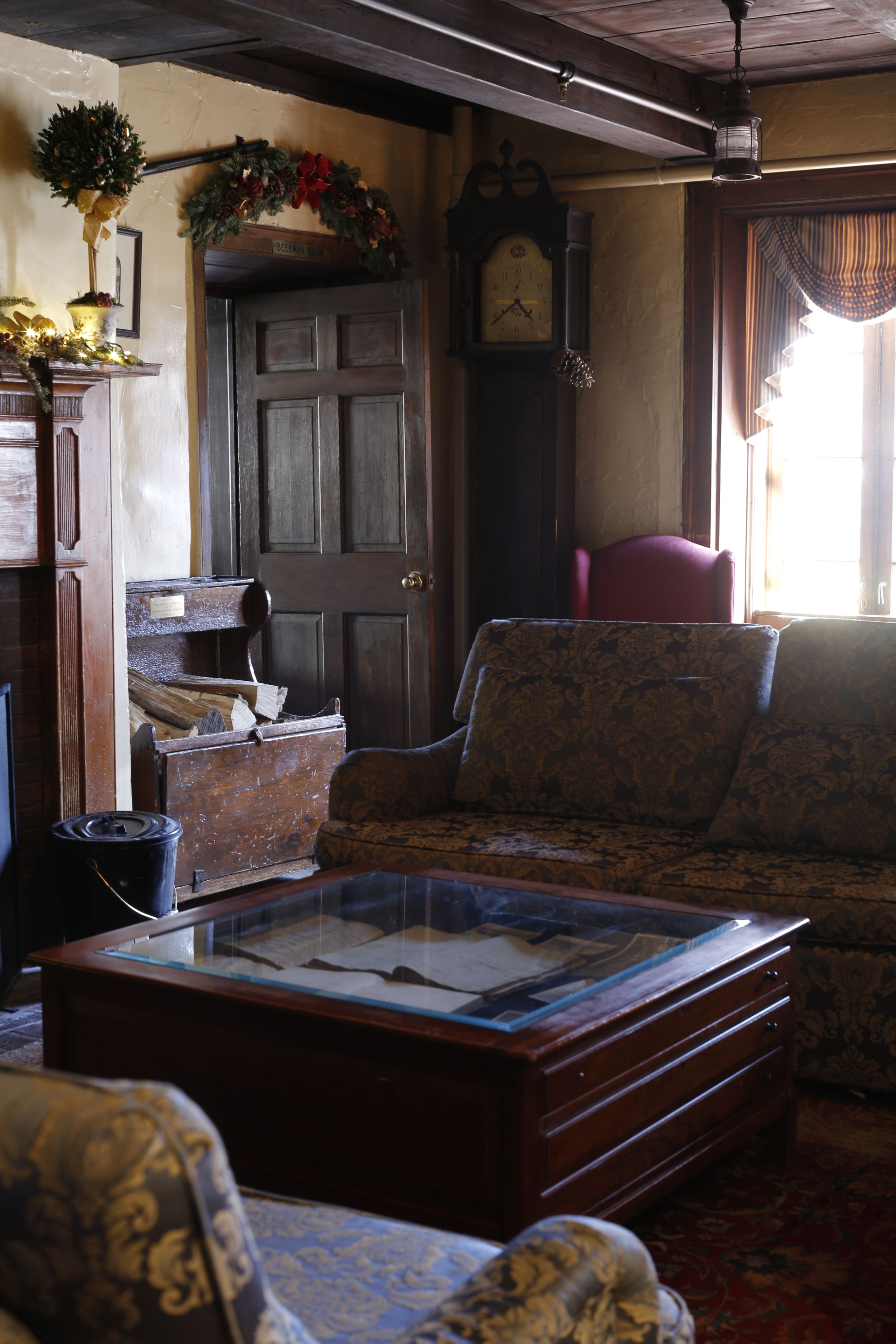 A traditional room with a wooden door, a clock, a sofa, and a glass-top coffee table.