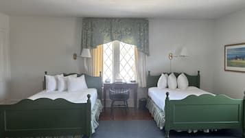 A room with two green beds, a small table, and a window with curtains.