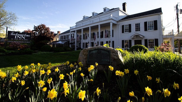 Un bâtiment blanc d’époque, doté d’un porche, de drapeaux américains et d’une enseigne indiquant « Beekman Arms Inn ».