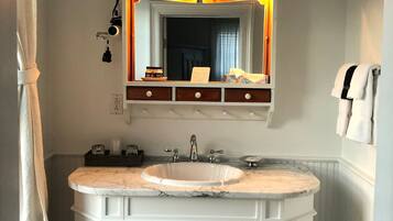 A bathroom with a large vanity, a mirror with a light, and a chandelier.