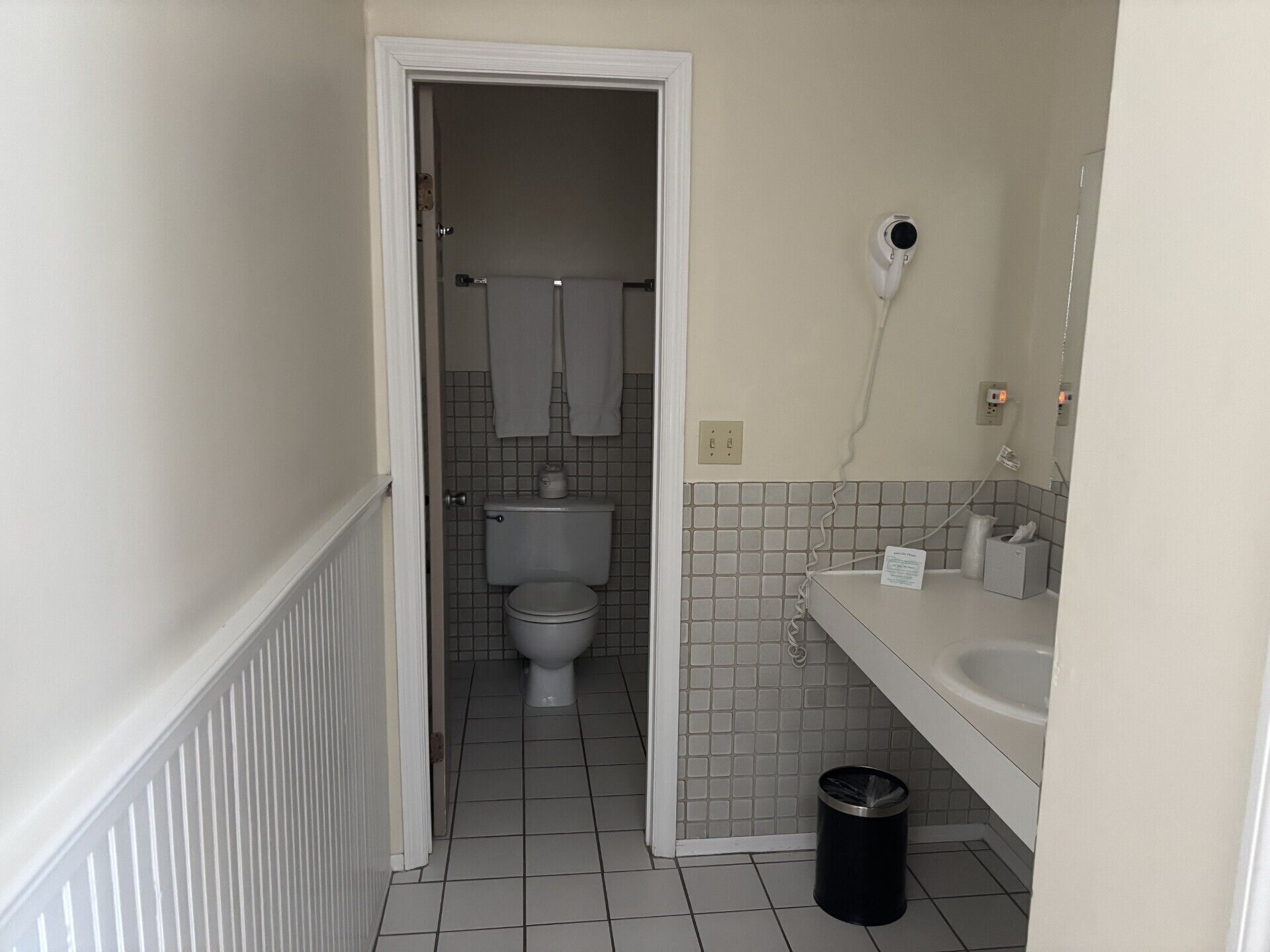 A bathroom with a toilet, a sink, and a trash can.