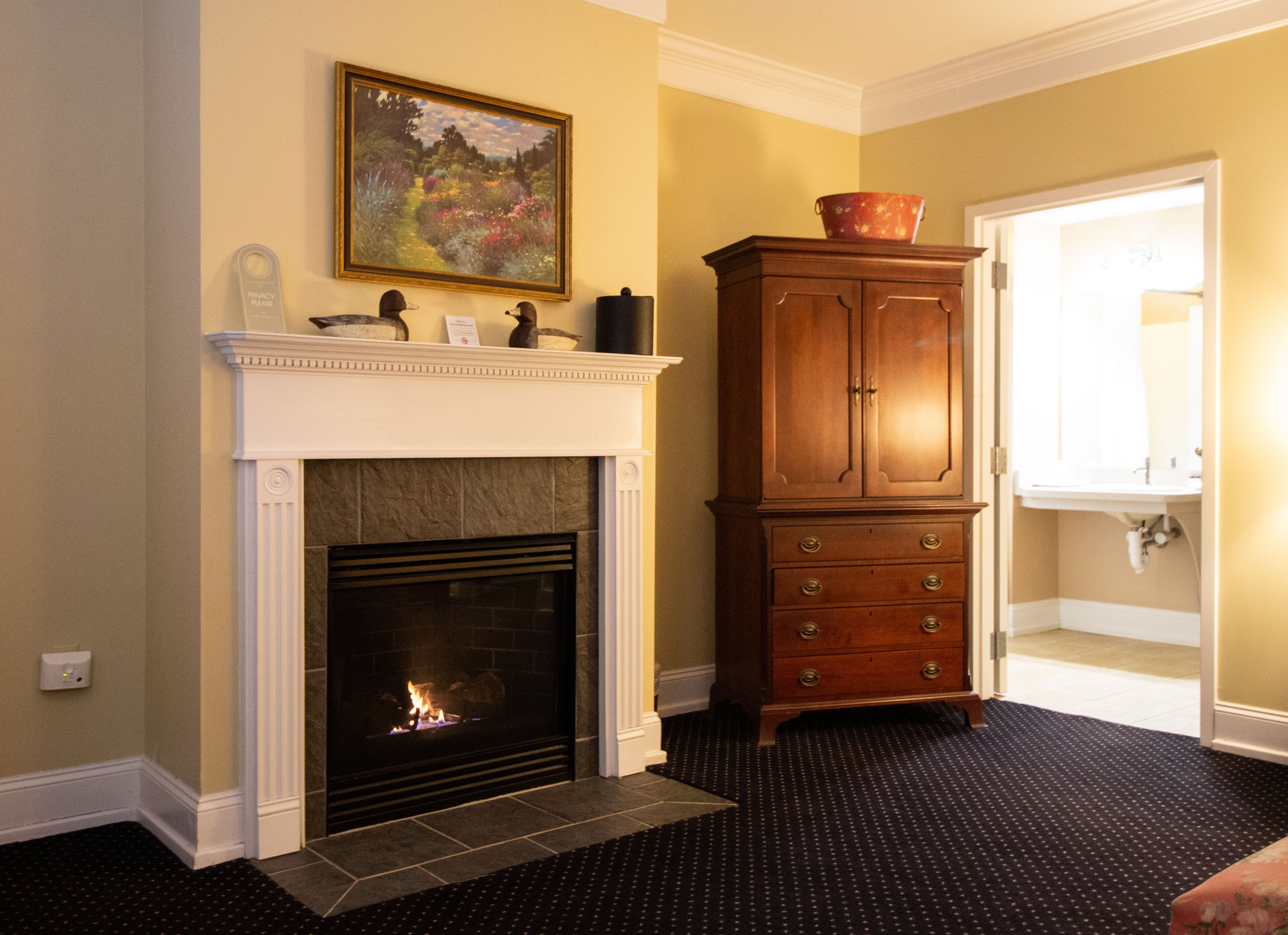 A room with a fireplace, a cabinet, and a bathroom visible through an open door.