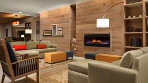 A modern living room with a fireplace, wooden panel walls, and a variety of seating options. - Country Inn & Suites by Radisson, Smithfield-Selma, NC (Smithfield)