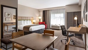 A hotel room with a bed, a desk, a chair, a table, and a sofa. - Country Inn & Suites by Radisson, Smithfield-Selma, NC (Smithfield)