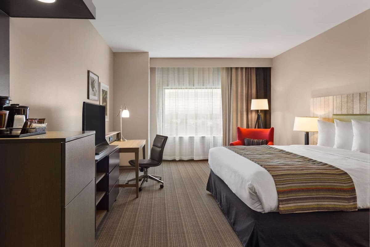 Ein Hotelzimmer mit Bett, Schreibtisch, Stuhl und Fernseher.