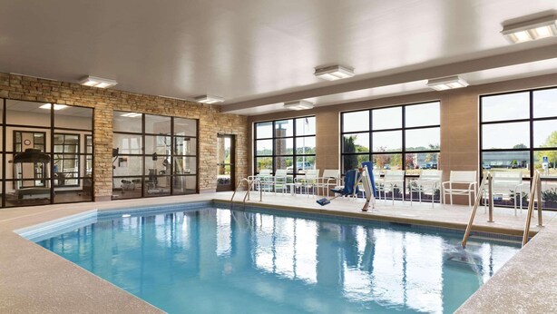 An indoor swimming pool with clear glass walls, a brick wall, and a view of the outside. - Country Inn & Suites by Radisson, Smithfield-Selma, NC (Smithfield)
