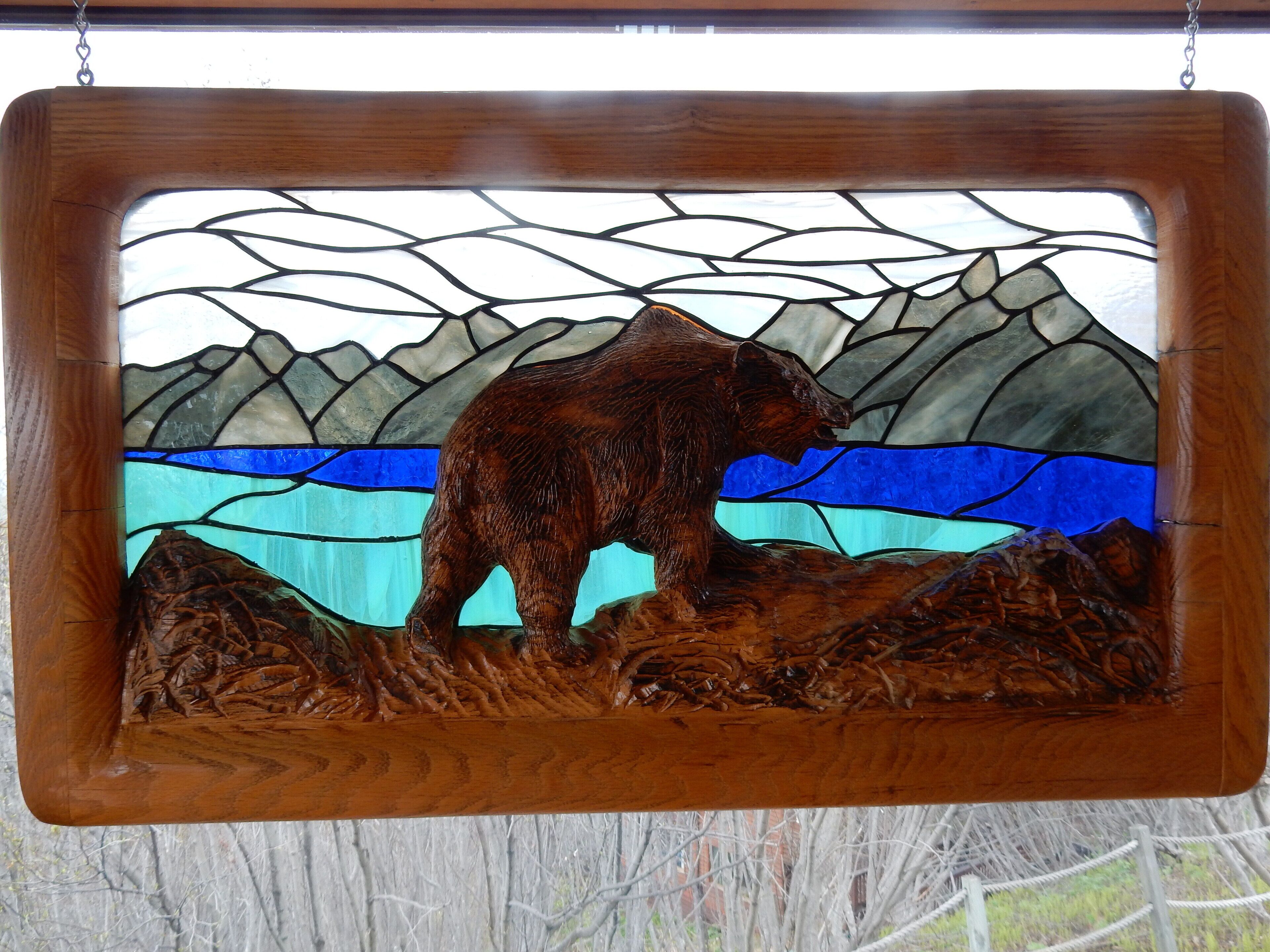 Une vitre décorée avec des motifs représentant un ours et des montagnes.