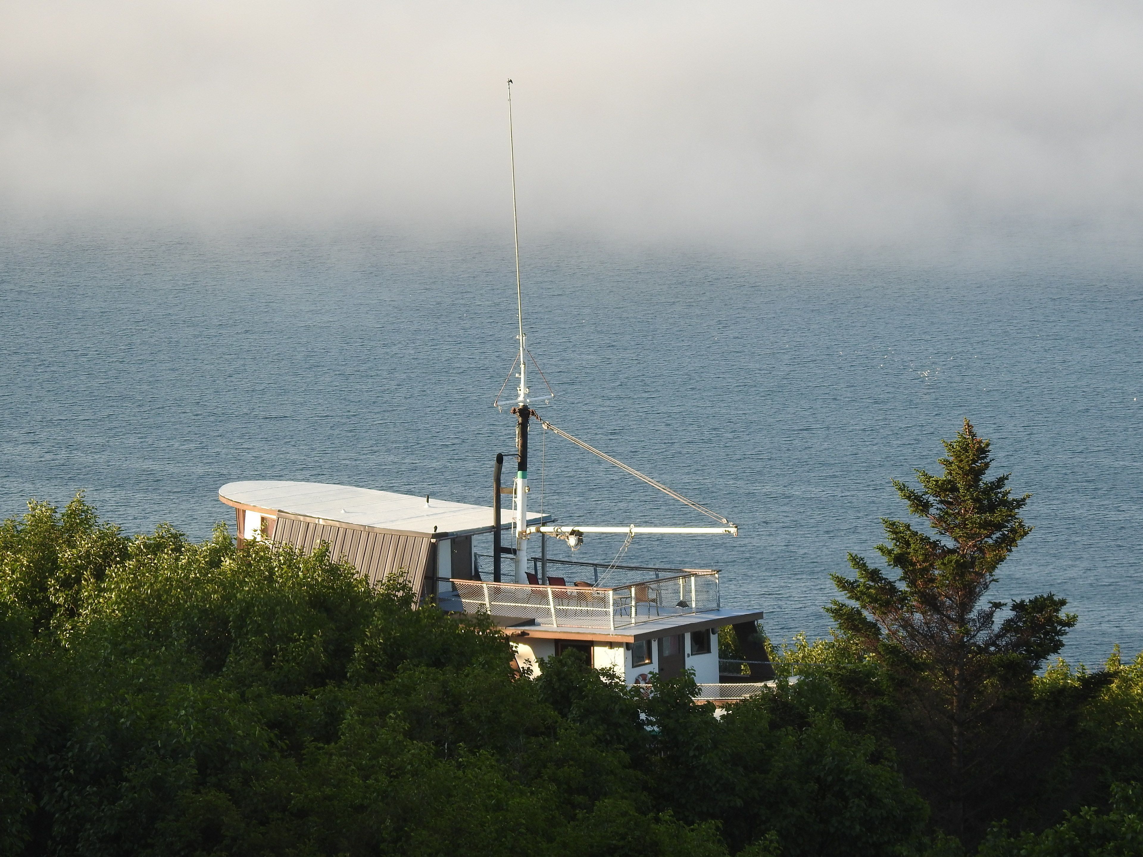 A coastal building with a large antenna, surrounded by dense greenery and overlooking the sea.