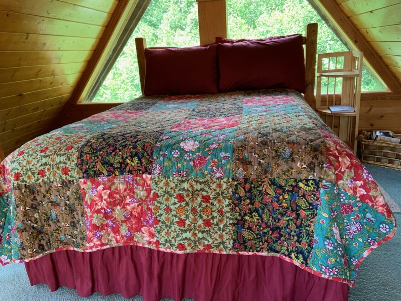 Ein Schlafzimmer mit einem großen Bett, einem Holzkopfstück und einem Fenster mit Blick auf Bäume.
