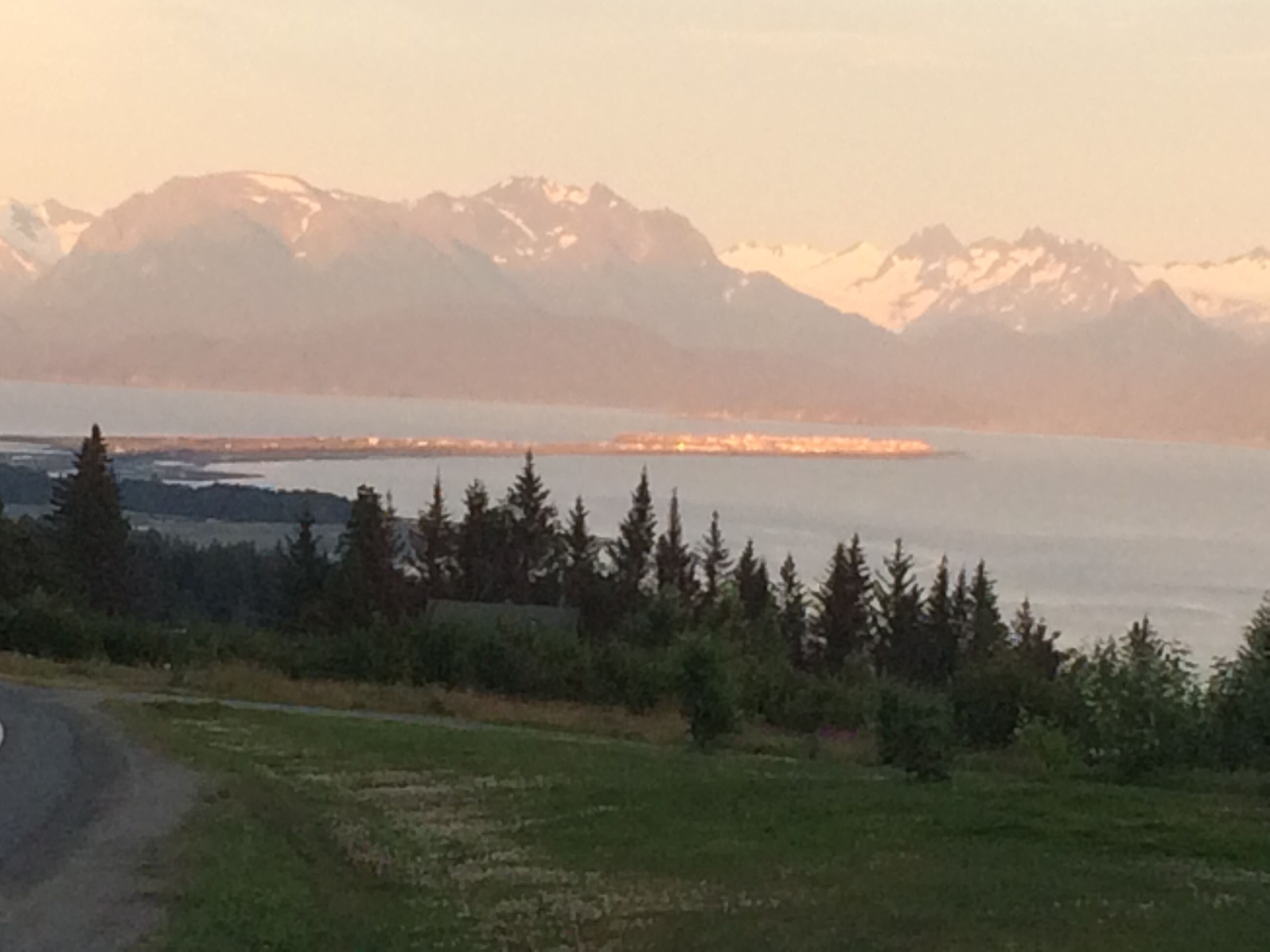 A mountainous landscape with a body of water and a distant city skyline.
