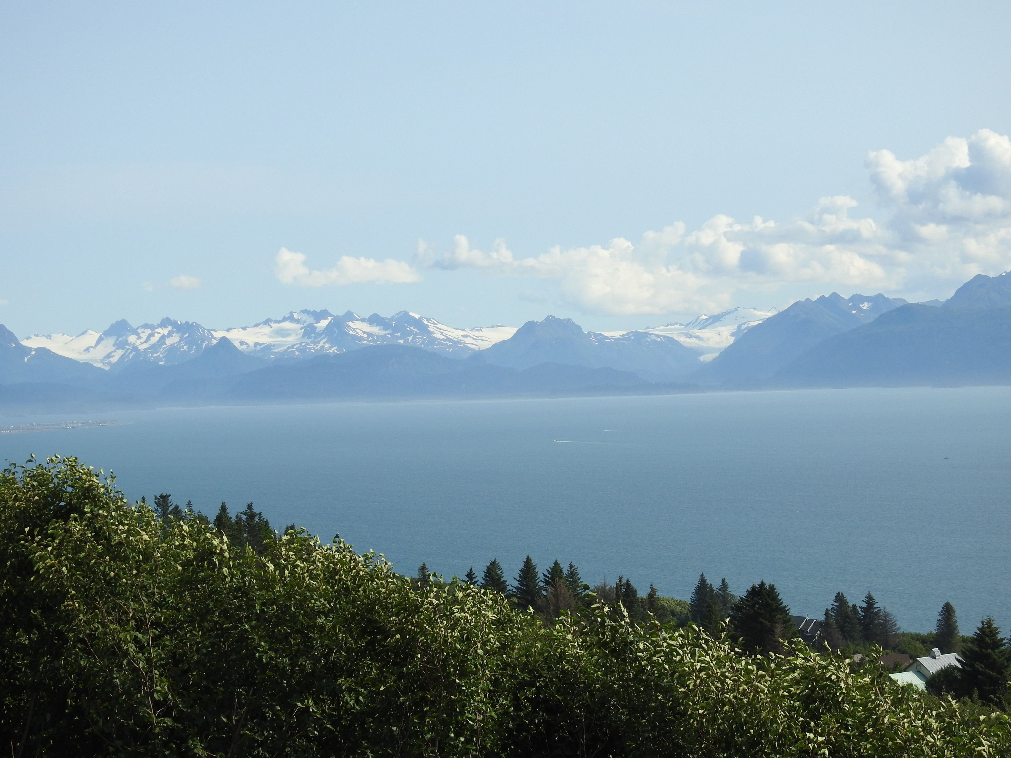 A mountainous landscape with a clear view of snow-capped peaks and a calm body of water.