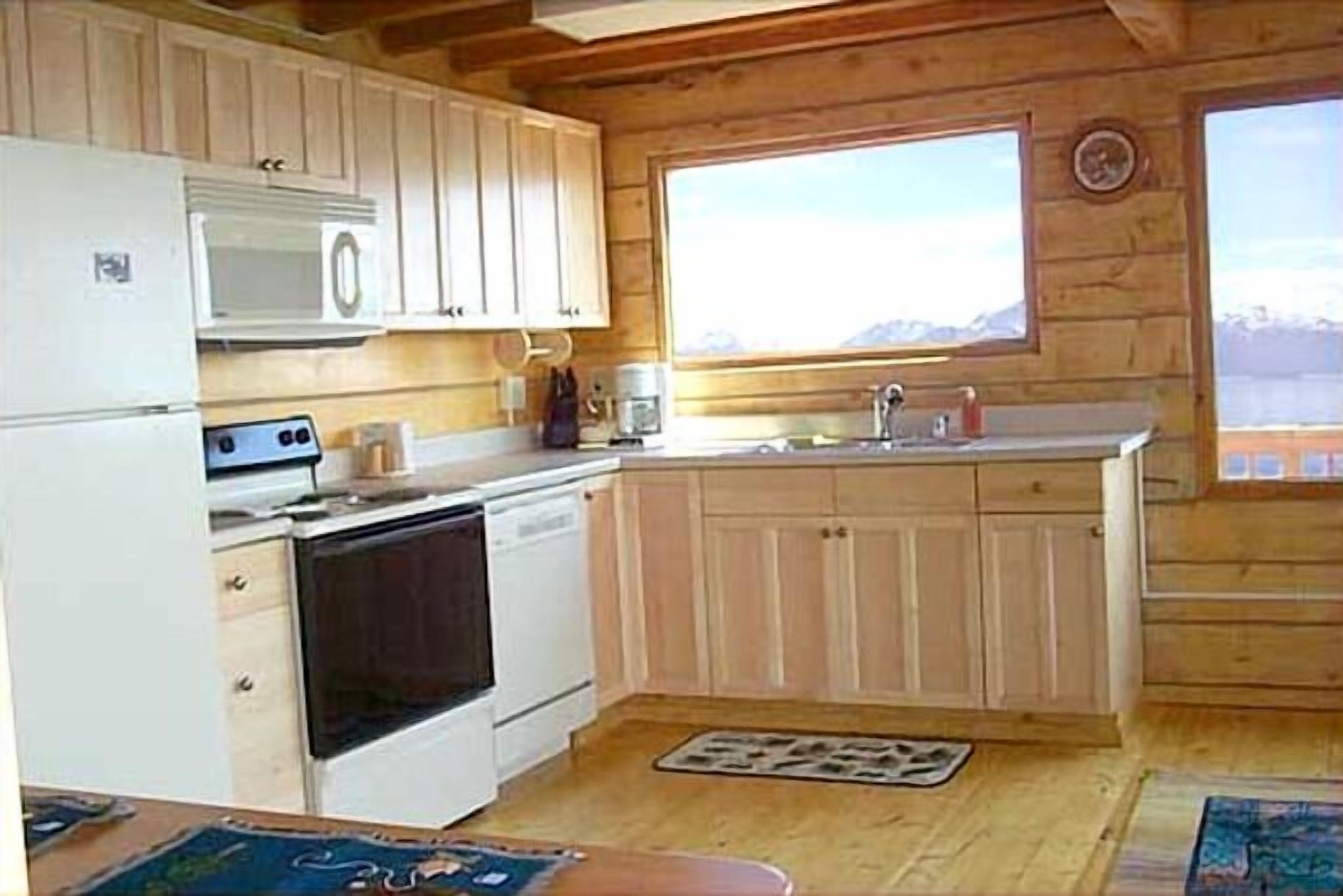 A compact kitchen with wooden cabinets, a microwave, a stove, and a sink.