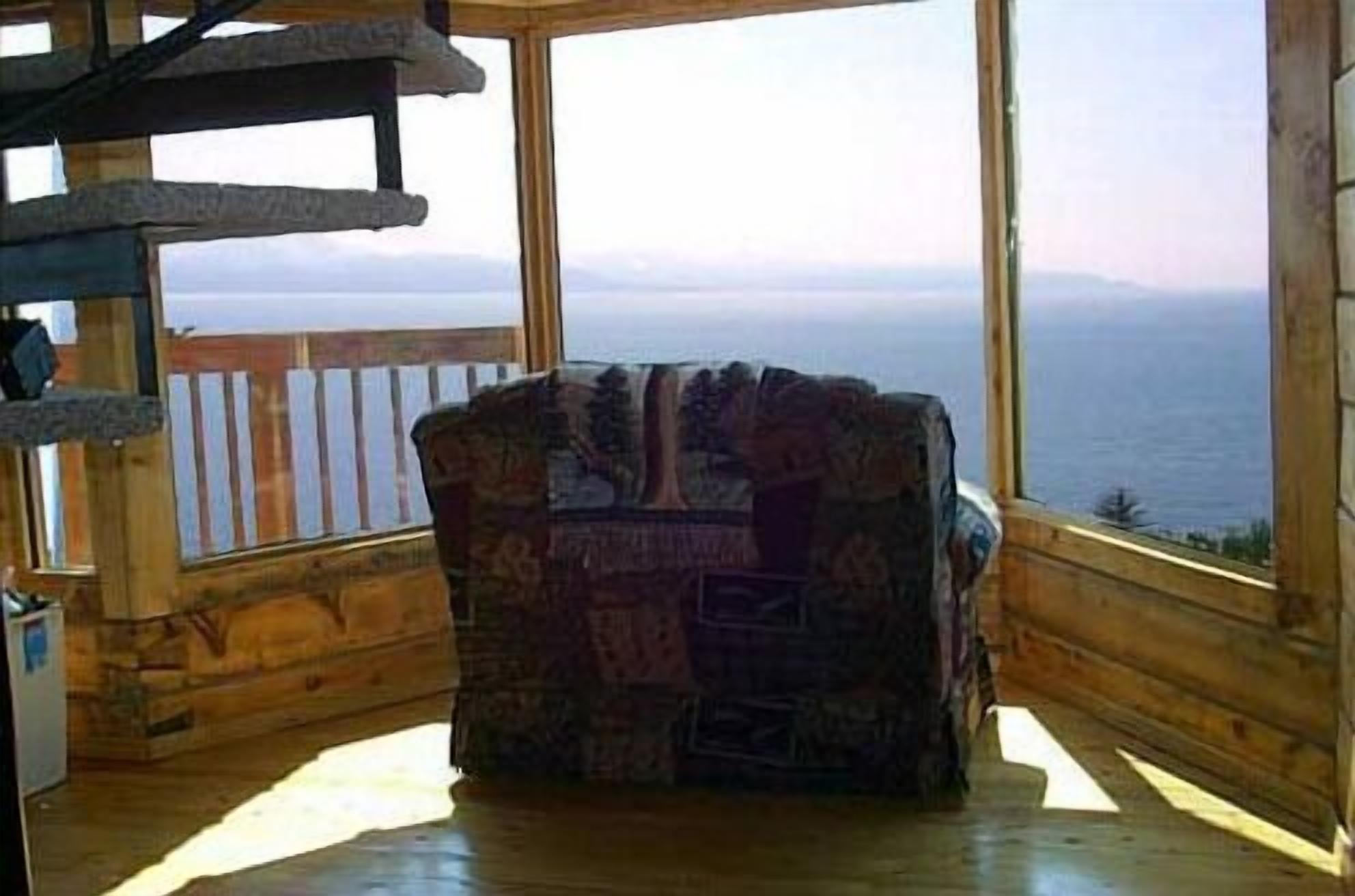 Une cabane en bois dotée d’une grande fenêtre donnant sur une étendue d’eau.