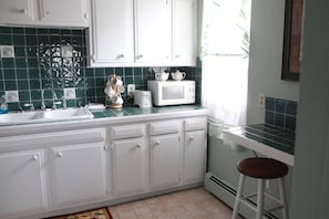 A kitchen with white cabinets, a microwave, and a sink.