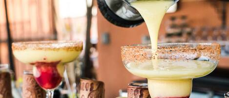 A bar setting with a drink being poured into a margarita glass.