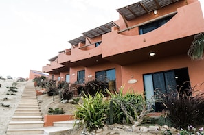Un edificio de varios pisos con diseño escalonado, con balcones y una variedad de plantas desérticas.