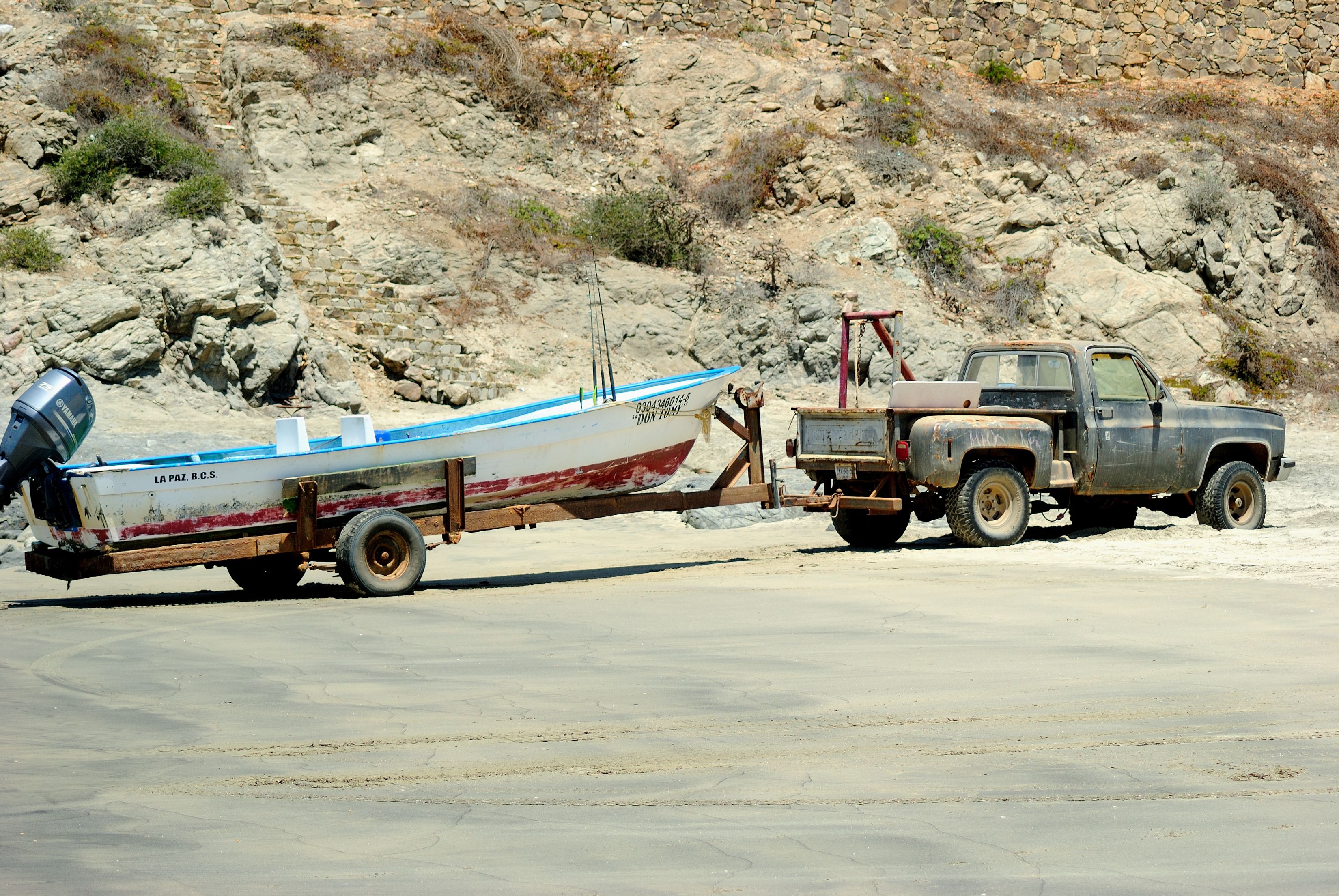 Un barco sobre un remolque, con una ladera rocosa al fondo.