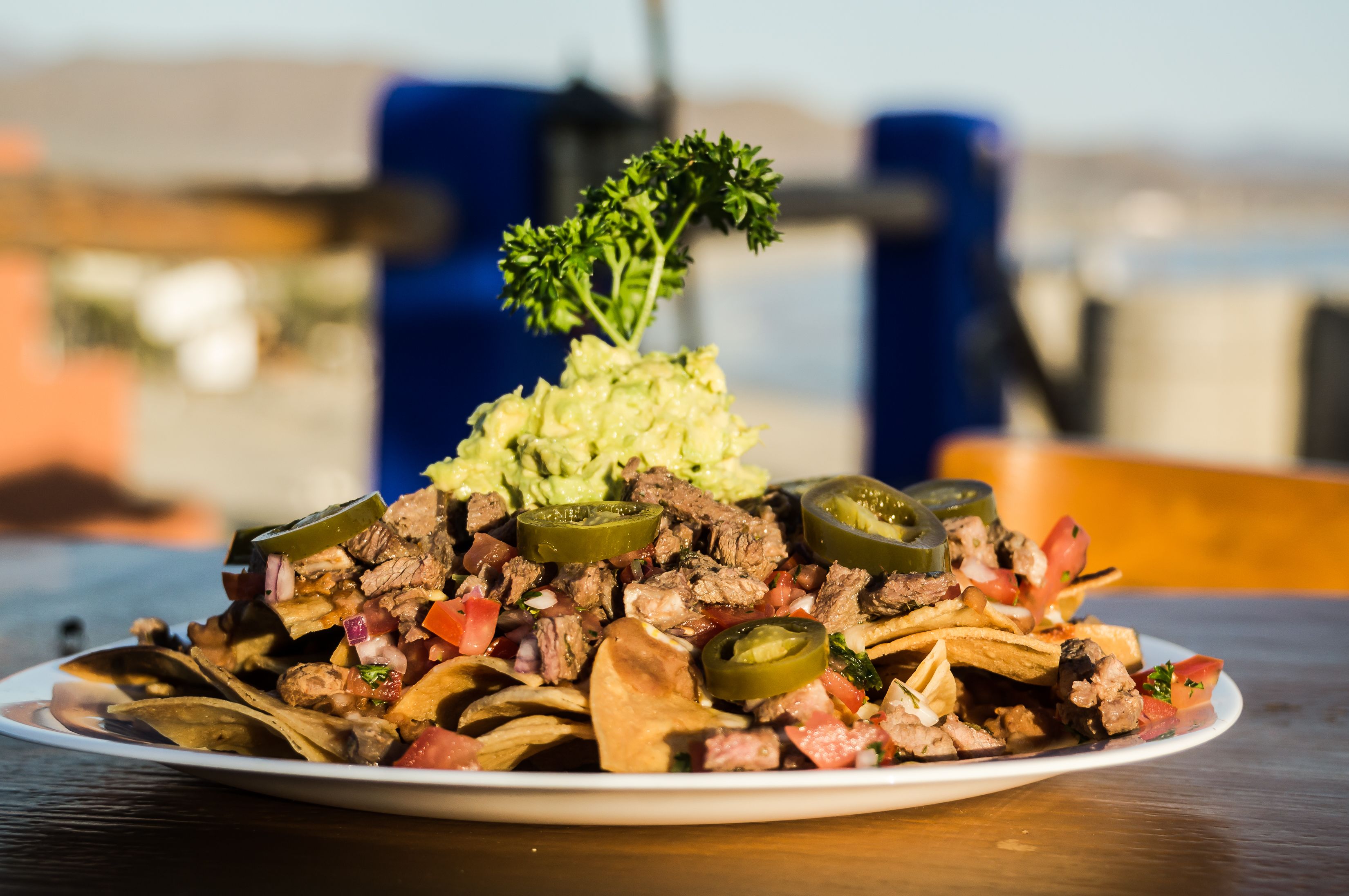 Un plato de nachos con diferentes ingredientes, como carne, queso y jalapeños, servido en un plato blanco.