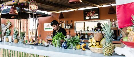 A bar area with a counter, various bottles, and tropical fruits.