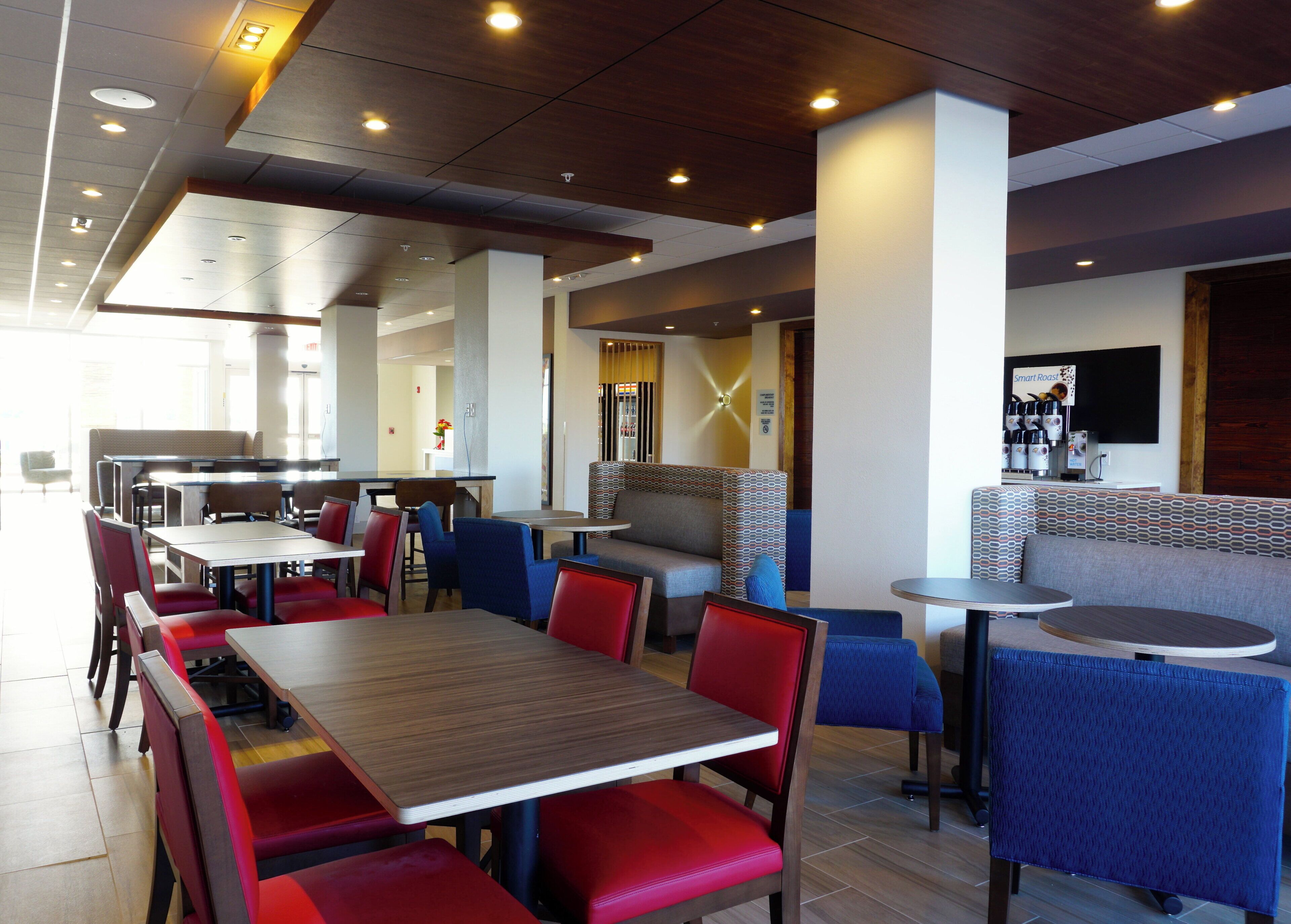 Interior moderno de restaurante con varias mesas y cabinas, una máquina de café y un letrero que dice 'Smart Roast'.