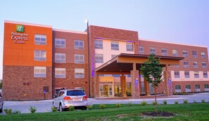 Un hotel Holiday Inn Express & Suites con fachada de ladrillo, acceso cubierto y estacionamiento.