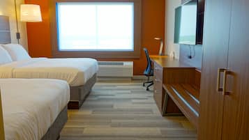 A hotel room with two beds, a desk, a TV, and a large window.