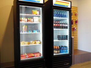 Two beverage vending machines stocked with various drinks and snacks. - Holiday Inn Express & Suites Omaha - Millard Area by IHG (Omaha)