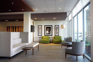 Un moderno vestíbulo de hotel con un sofá modular, dos sillones, una mesita y obras de arte en las paredes.