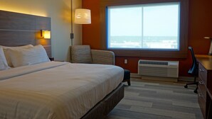 A hotel room with a large bed, a chair, a desk, and a window with a view. - Holiday Inn Express & Suites Omaha - Millard Area by IHG (Omaha)