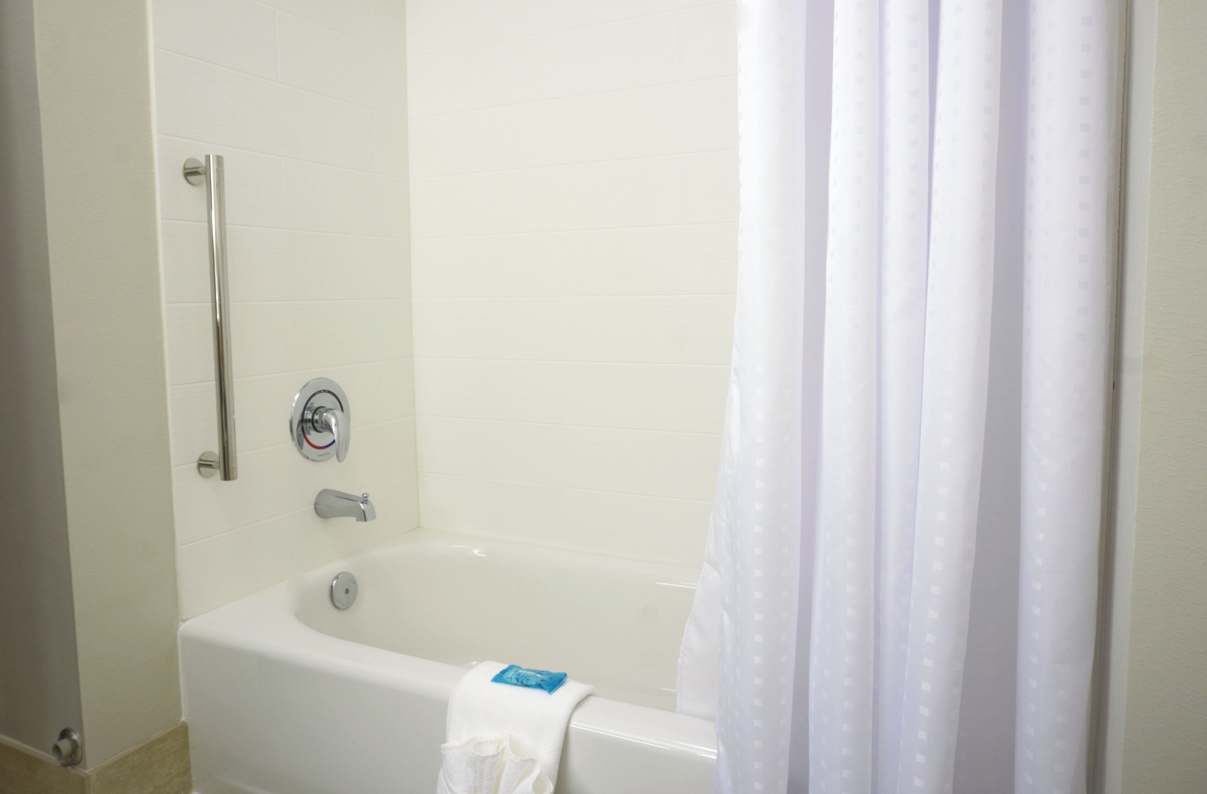 Un baño con una bañera blanca, ducha y cortina.