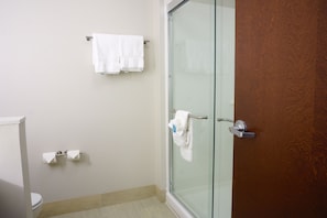 A bathroom with a toilet, a glass shower enclosure, and a towel rack with two white towels. - Holiday Inn Express & Suites Omaha - Millard Area by IHG (Omaha)