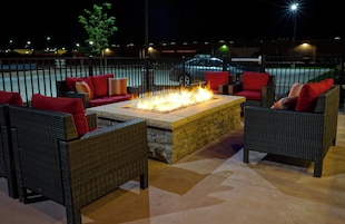 An outdoor seating area with wicker furniture and a central fire feature.