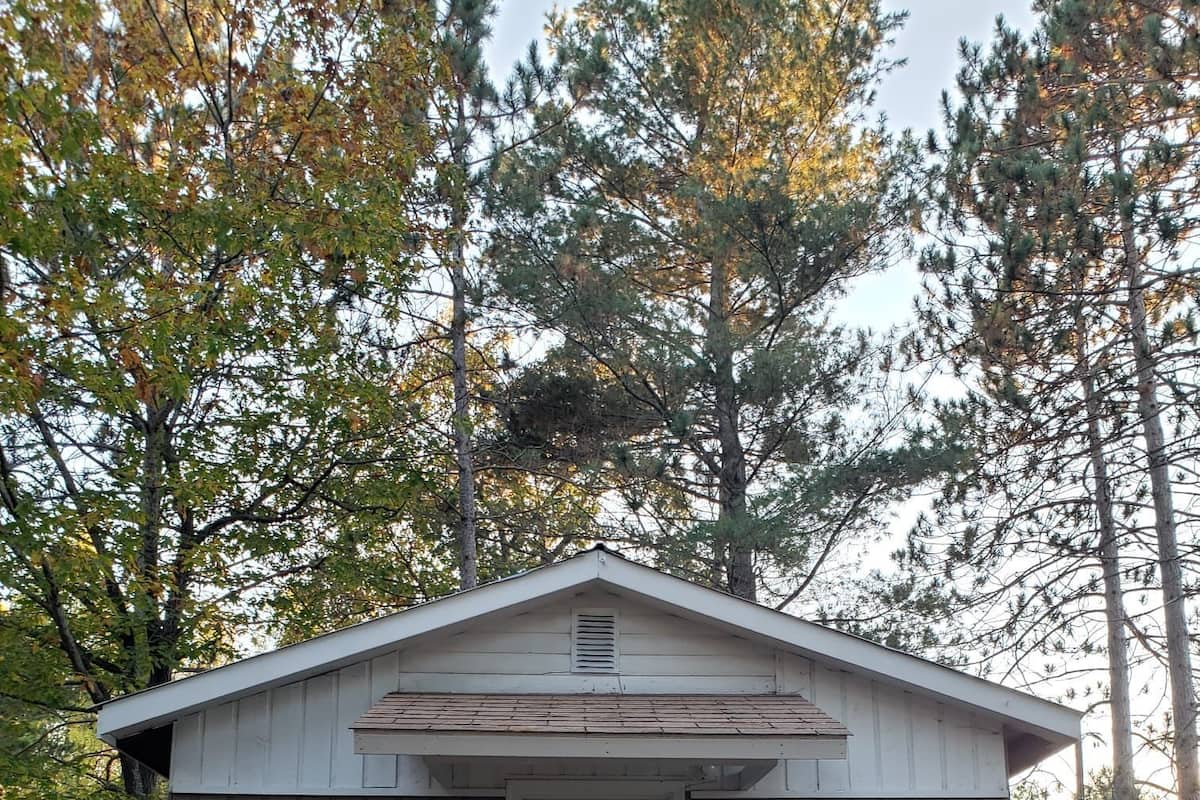Une petite cabane en bois avec une porte blanche, une pancarte indiquant « Bienvenue » et le chiffre « 2 » sur le côté.