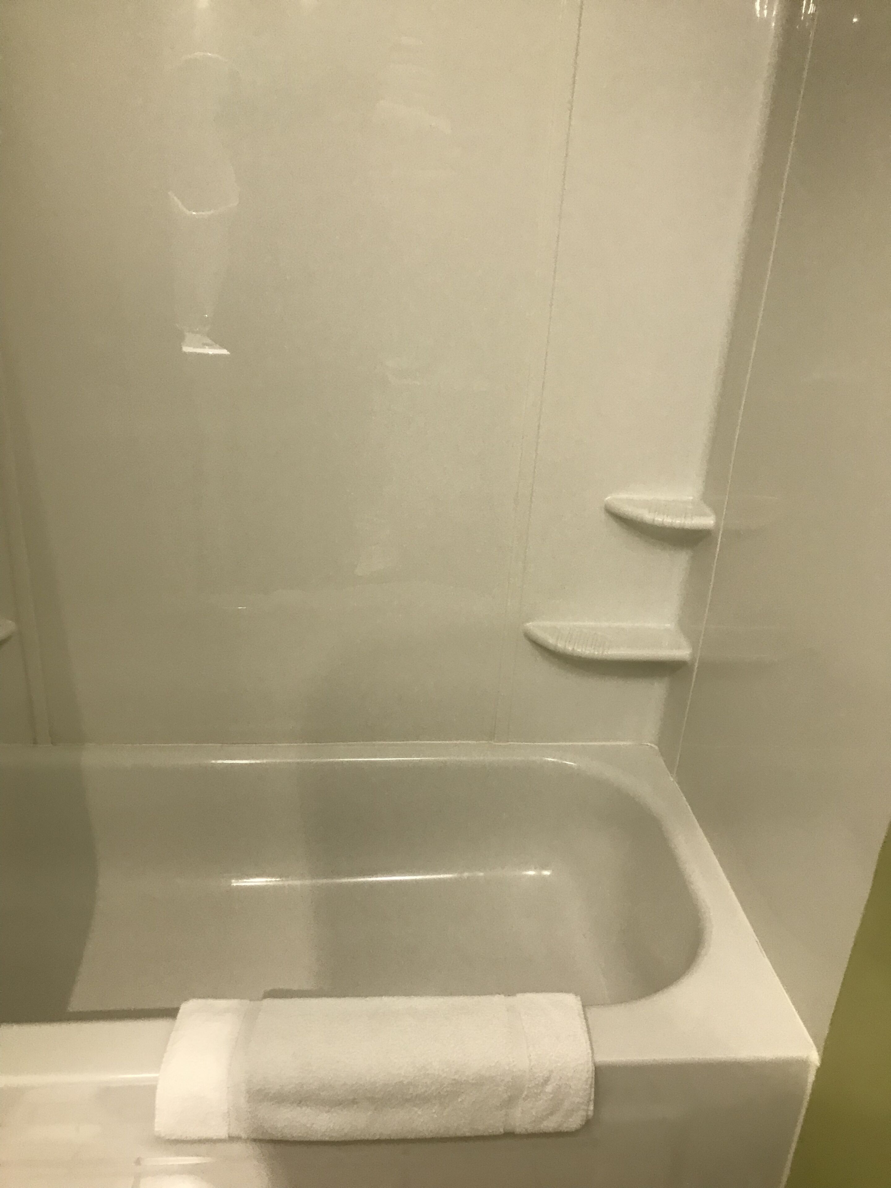 Un baño moderno con bañera de hidromasaje envuelta en vidrio, una toalla blanca y cabina de ducha de vidrio.