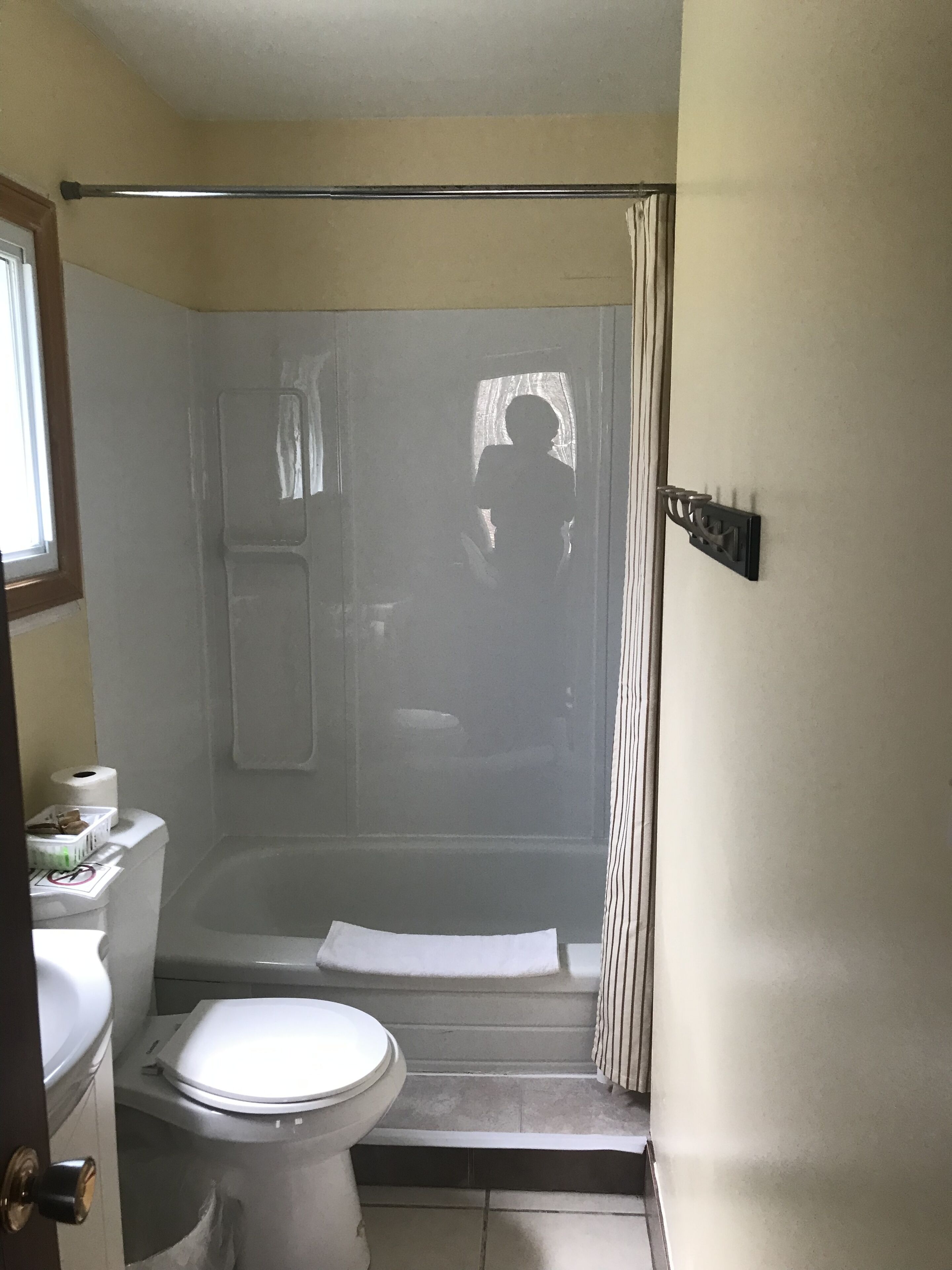 A bathroom with a toilet, shower, and a towel rack.