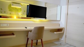 Une chambre moderne équipée d’un bureau intégré, d’une chaise, d’un téléviseur à écran plat et d’un climatiseur fixé au mur.