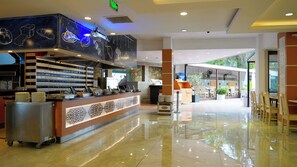 A hotel lobby with a reception desk, a buffet area, and a seating area with tables and chairs. - Club Aqua Plaza (Alanya)