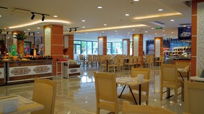 A spacious dining area with multiple tables and chairs, a buffet counter, and decorative wall panels. - Club Aqua Plaza (Alanya)
