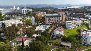 A resort with a swimming pool, multiple buildings, and a mountainous backdrop. - Club Aqua Plaza (Alanya)