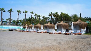 Ein Strand mit Reetdachschirmen und Liegestühlen.