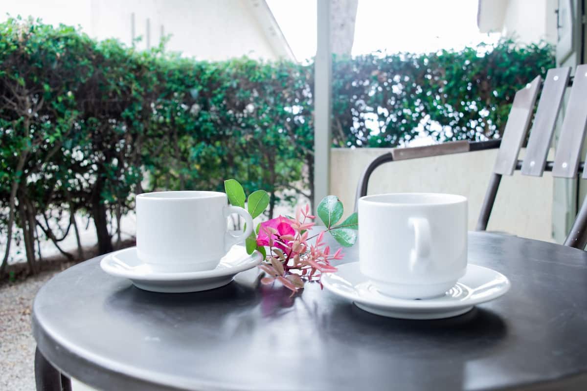 Two white cups on a round table with a metal chair.
