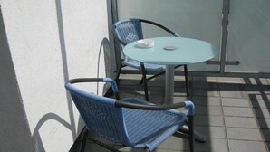 Un pequeño espacio al aire libre con una mesa redonda y dos sillas azules.