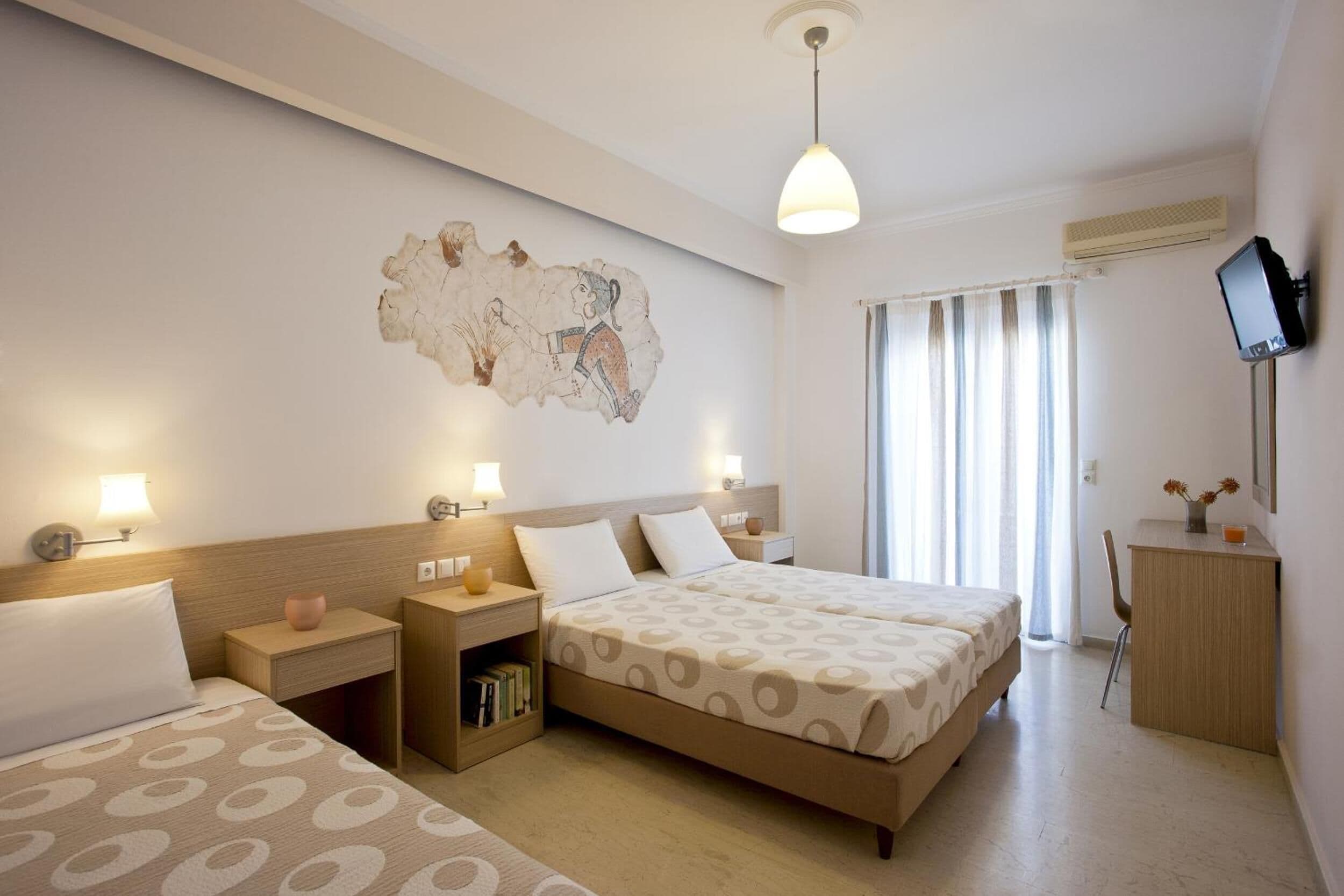 A hotel room with a bed, bedside tables, a desk, and a television.